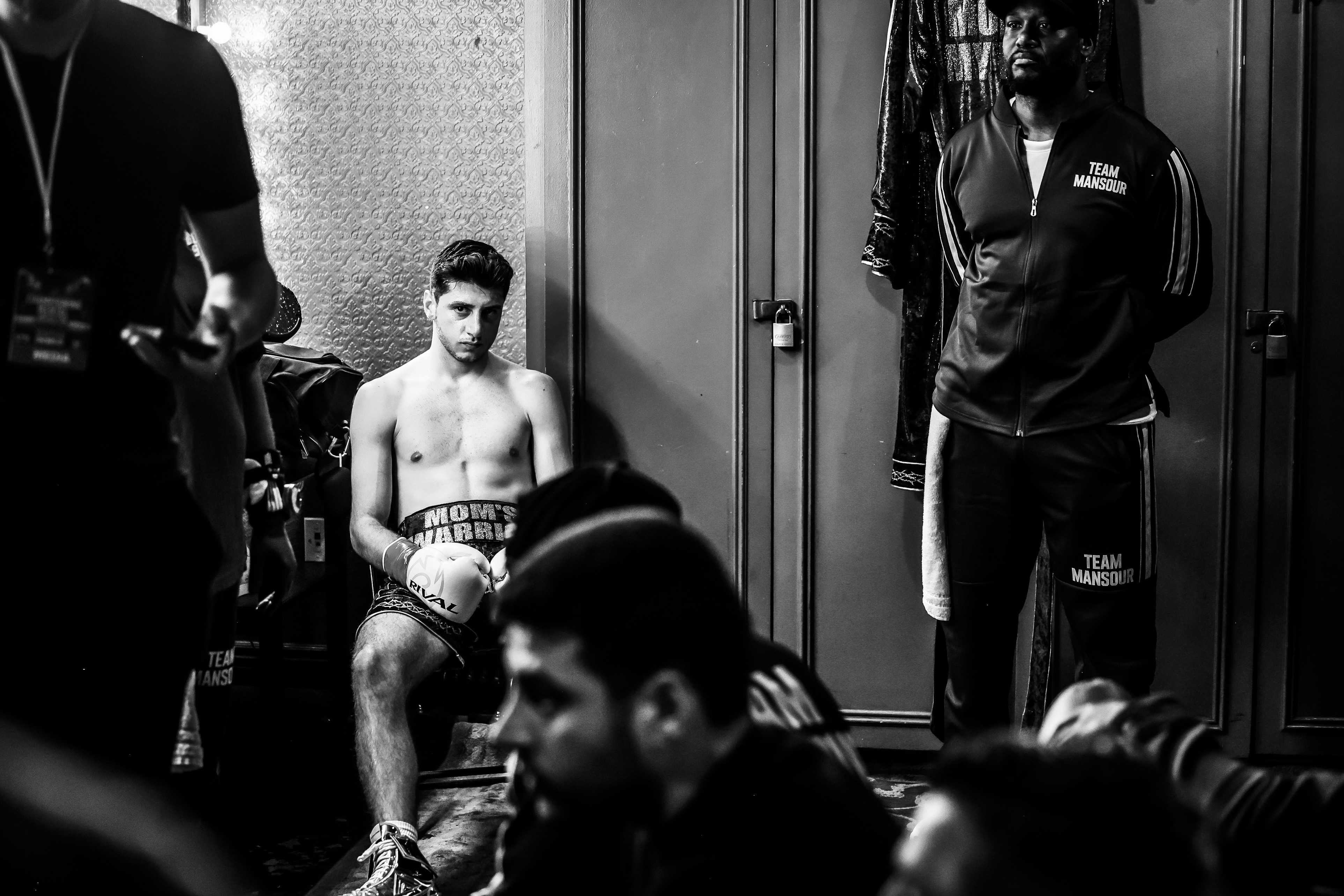 Jonny Mansour sitting in the locker room in 'Mom's Warrior' trunks before walking out